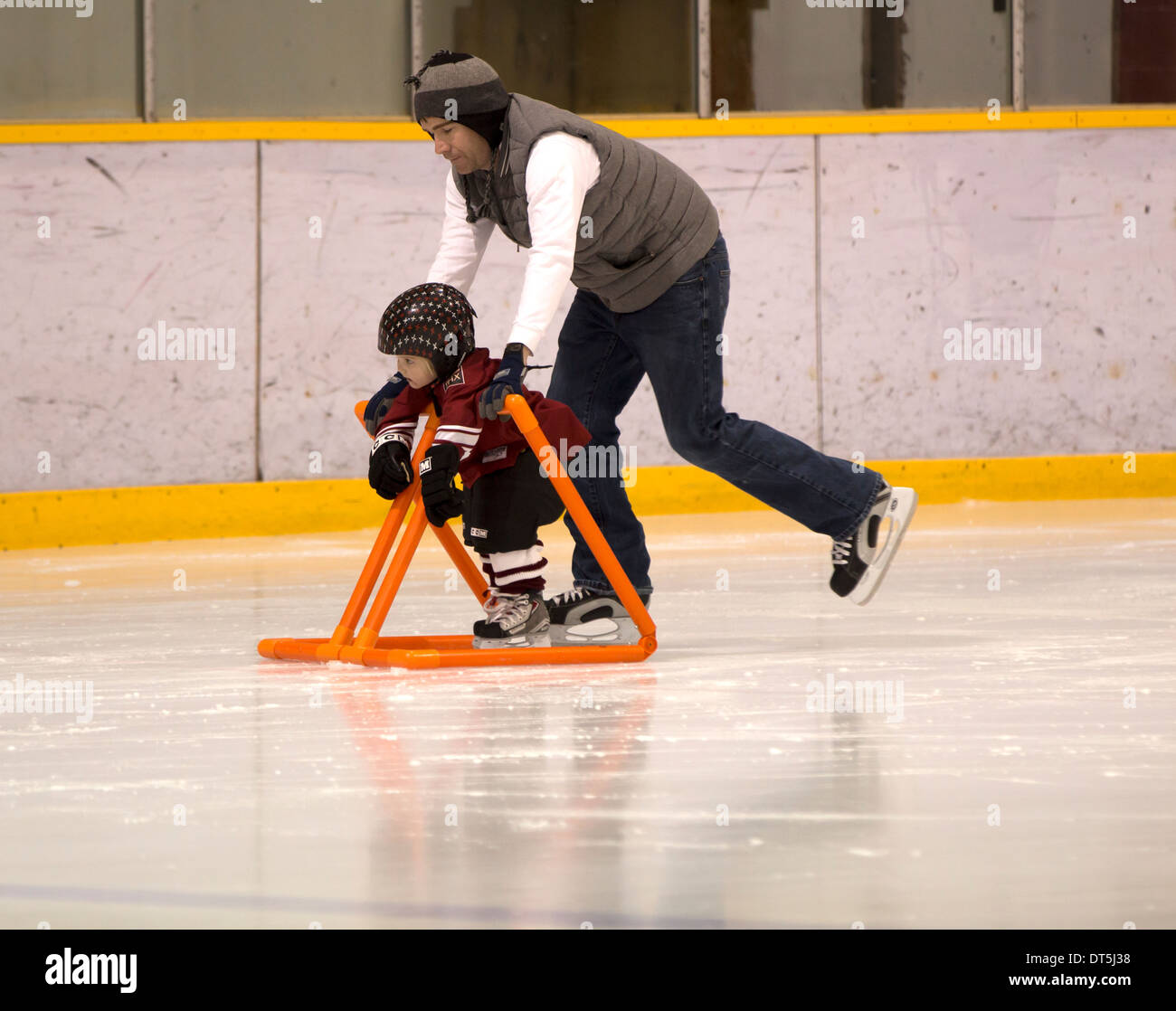 Father Teaching Child To Ice Skate With Assistance Stock Photo