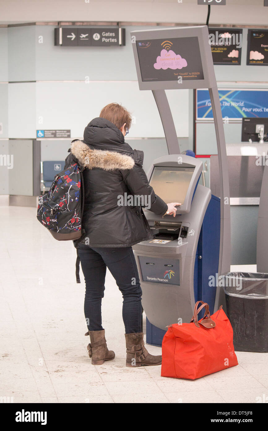 Woman using self help check in machine for Westjet at Pearson International Airport, Toronto, Ontario Canada Stock Photo