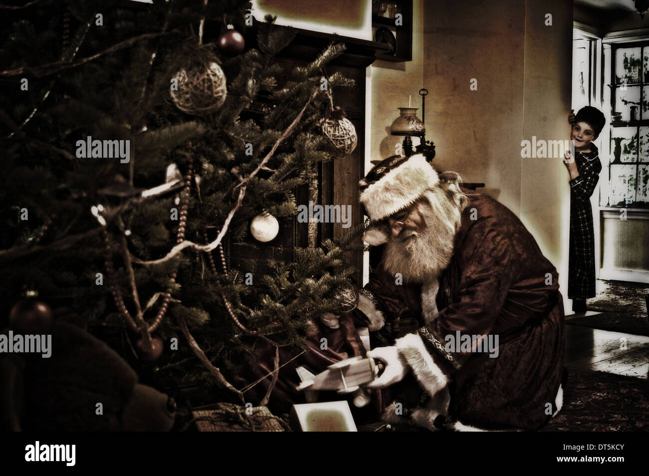 A little boy seeing Santa Claus putting presents under the Christmas ...