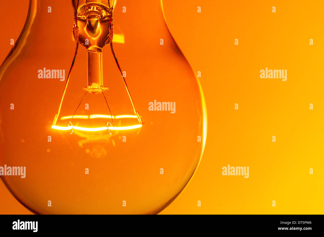 Close up glowing light bulb on orange background Stock Photo