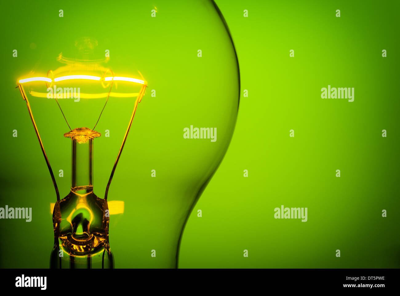 Close up glowing light bulb on green background Stock Photo - Alamy