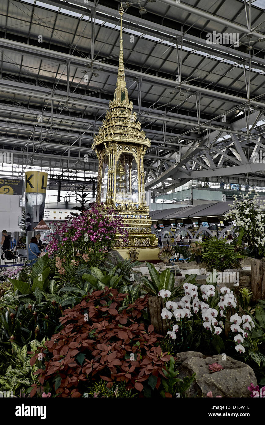 Gold feature Buddhist spirit house encasement and decorative flower display at Suvarnabhumi airport Bangkok Thailand S. E. Asia Stock Photo