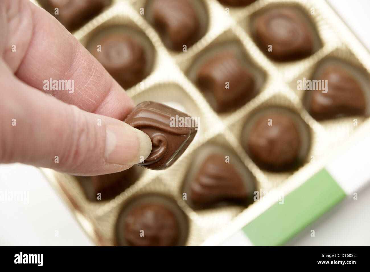 Woman helping herself to a chocolate from a box of chocolates Stock Photo