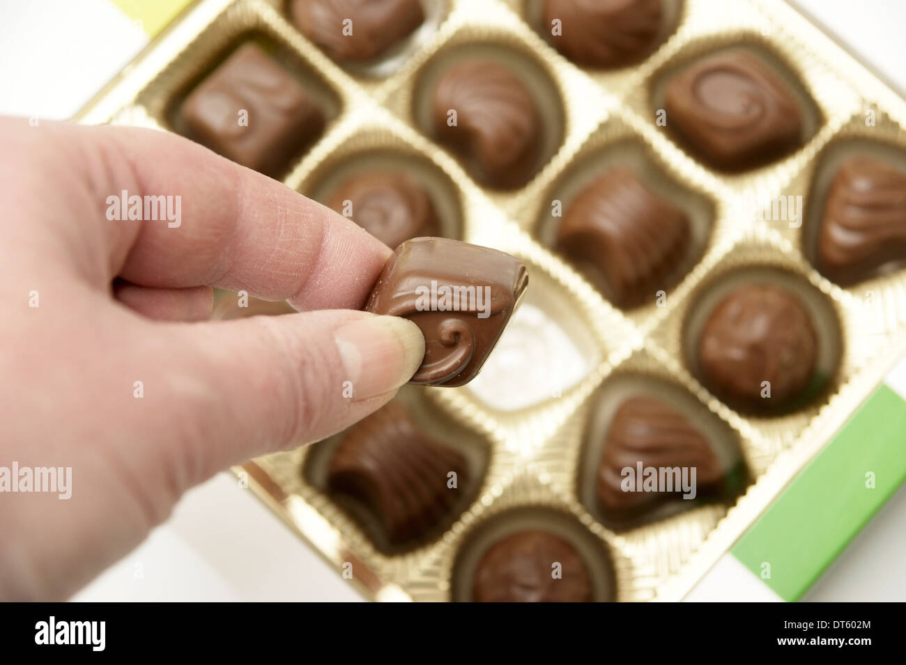 Woman helping herself to a chocolate from a box of chocolates Stock Photo