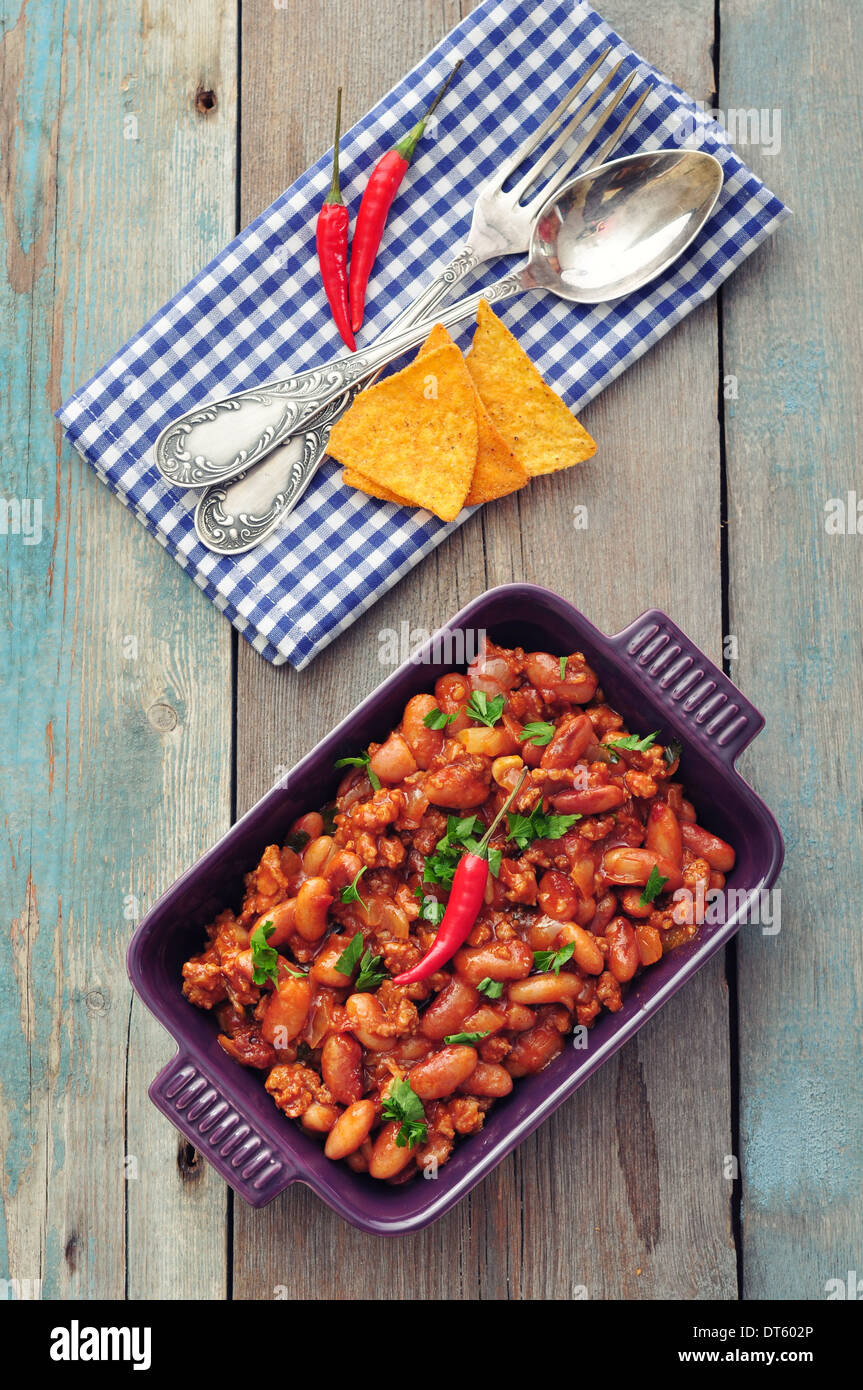 Chili Con Carne in baking mold with tortilla chips on wooden background Stock Photo