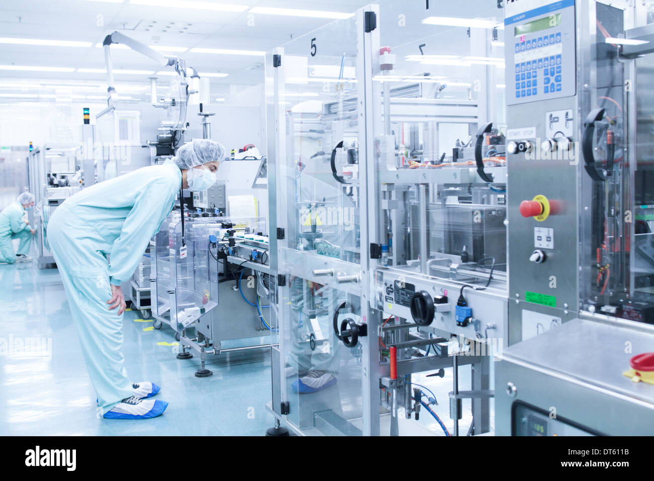 Laboratory technician bending to take closer look at machine Stock Photo