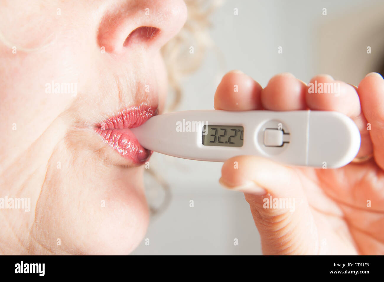 Woman taking her own temperature using digital thermometer Stock Photo