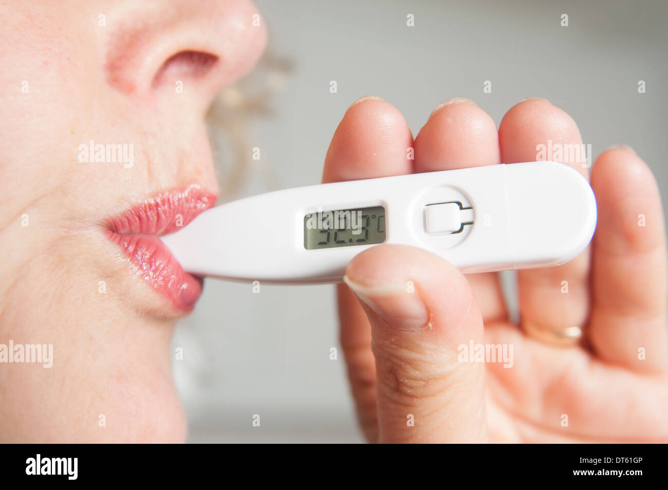 Woman taking her own temperature using digital thermometer Stock Photo