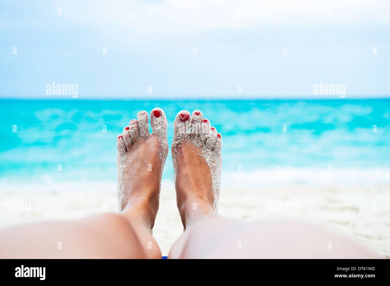 Close up of female legs and feet sunbathing on beach Stock Photo