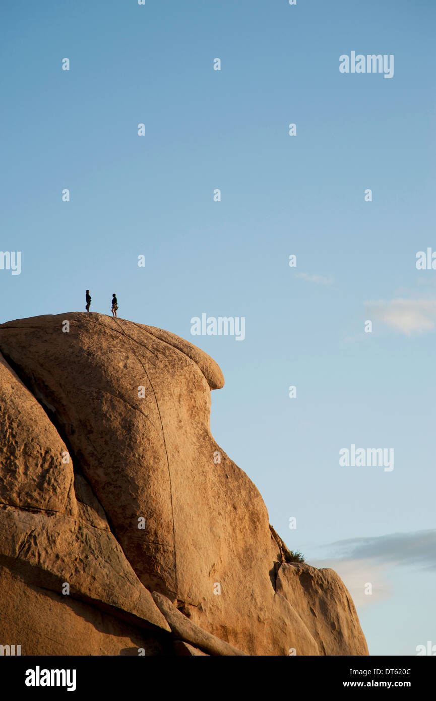 Two people on top of high rock formation, Joshua Tree national park, California, USA Stock Photo