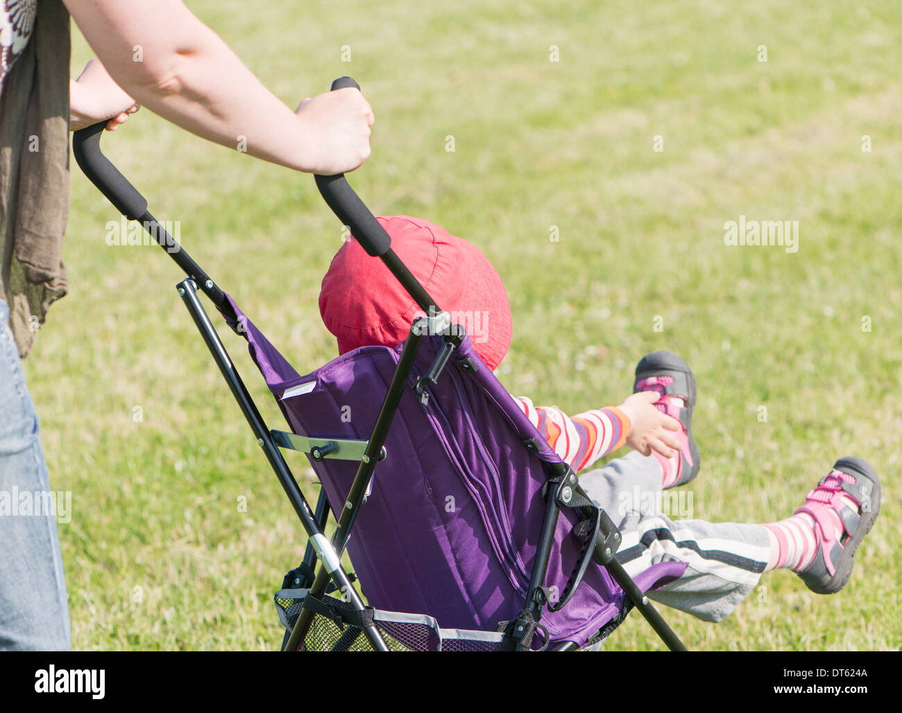 Mother walking in park with daughter in baby stroller Stock Photo