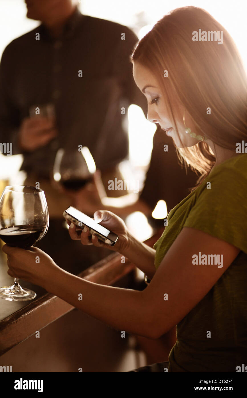 Businesswoman looking at cellphone in a wine bar Stock Photo