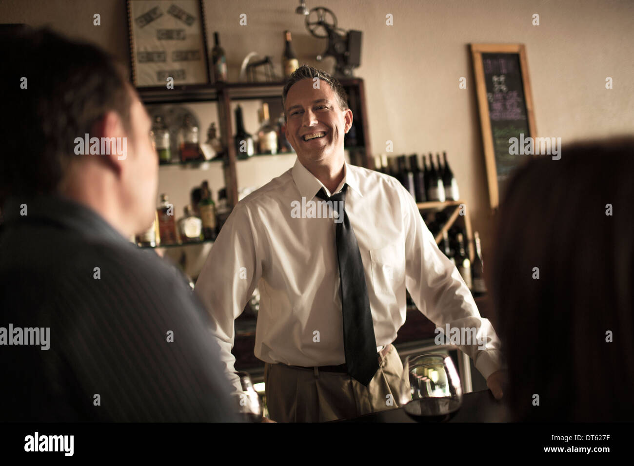 Bartender chatting with customers in wine bar Stock Photo