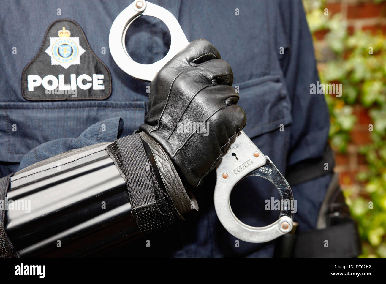England, Society, Law and Order, Detail of Police law enforcement officer wearing body armour and holding handcuffs. Stock Photo