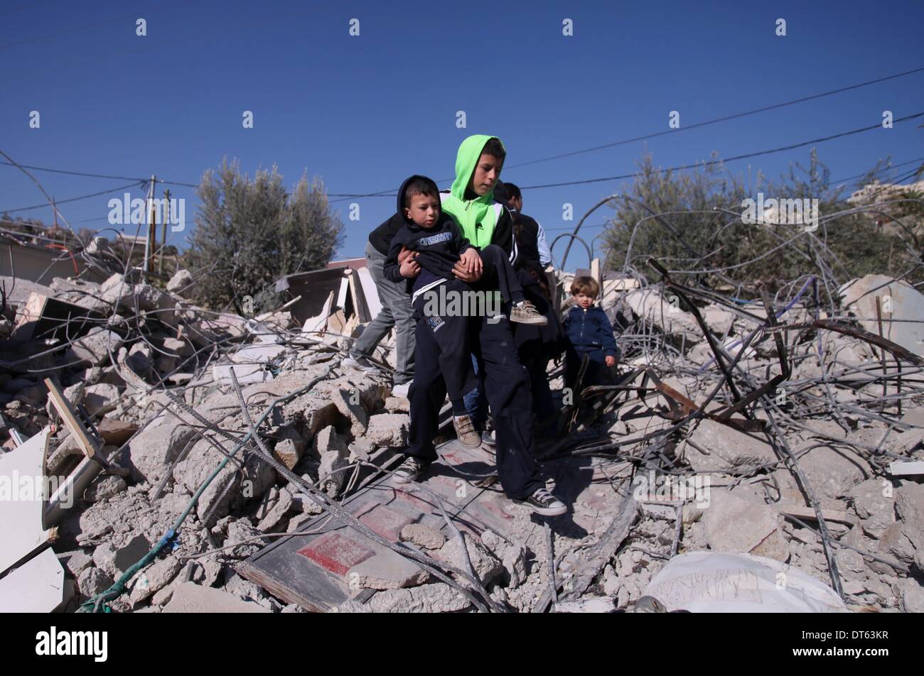 A Palestinian man stands with his children on the rubble of his house ...
