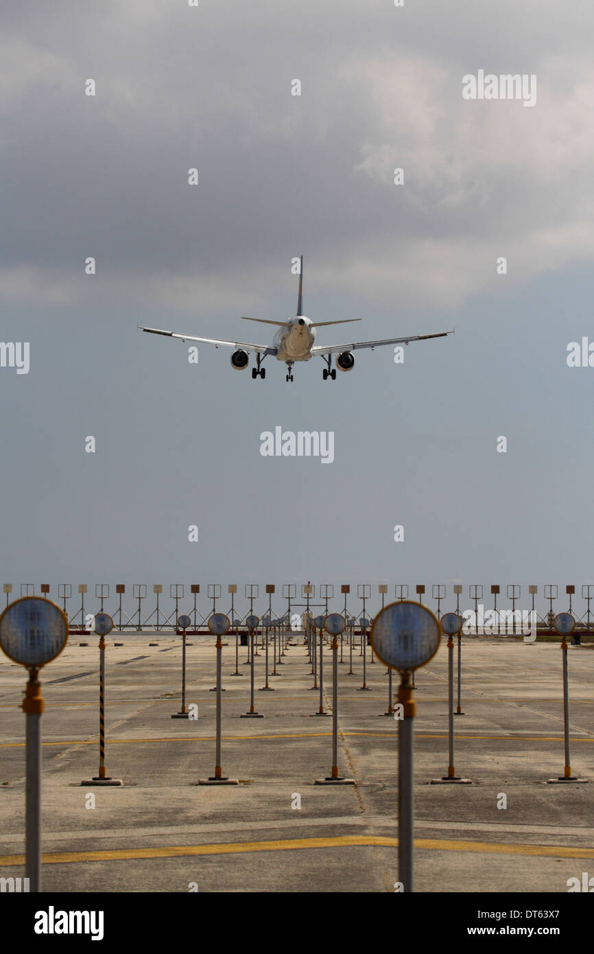 Commercial air transport flight. Airplane arriving and overflying airport runway approach lights moments before landing Stock Photo