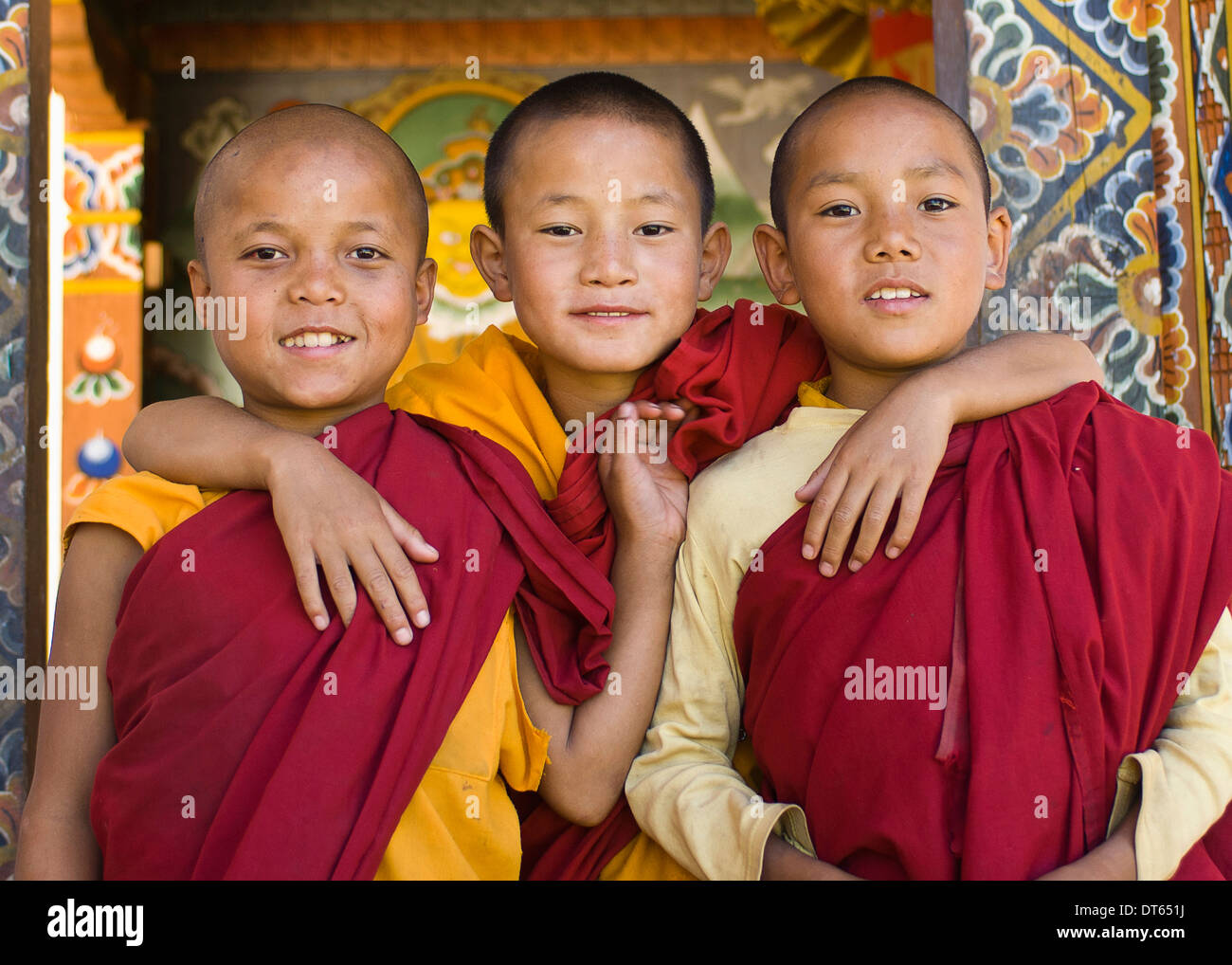 Bhutan, South Asia, Punakha, Three young novice boy monks standing in doorway of Chimi Lakhang temple in the old capital. Stock Photo