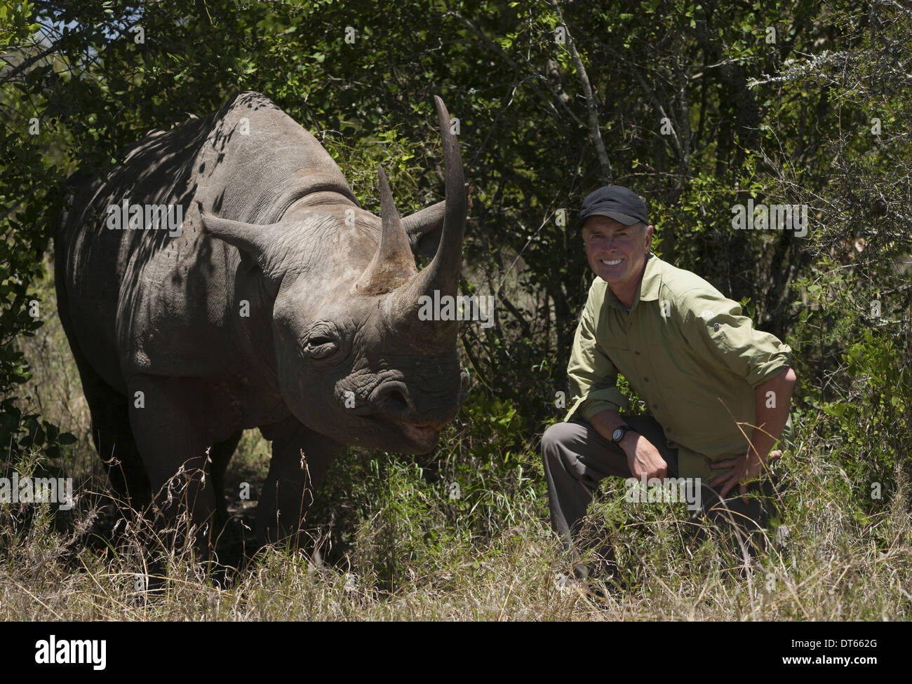 Art Wolfe, photographer kneeling next to a white rhinoceros in Kenya. Stock Photo