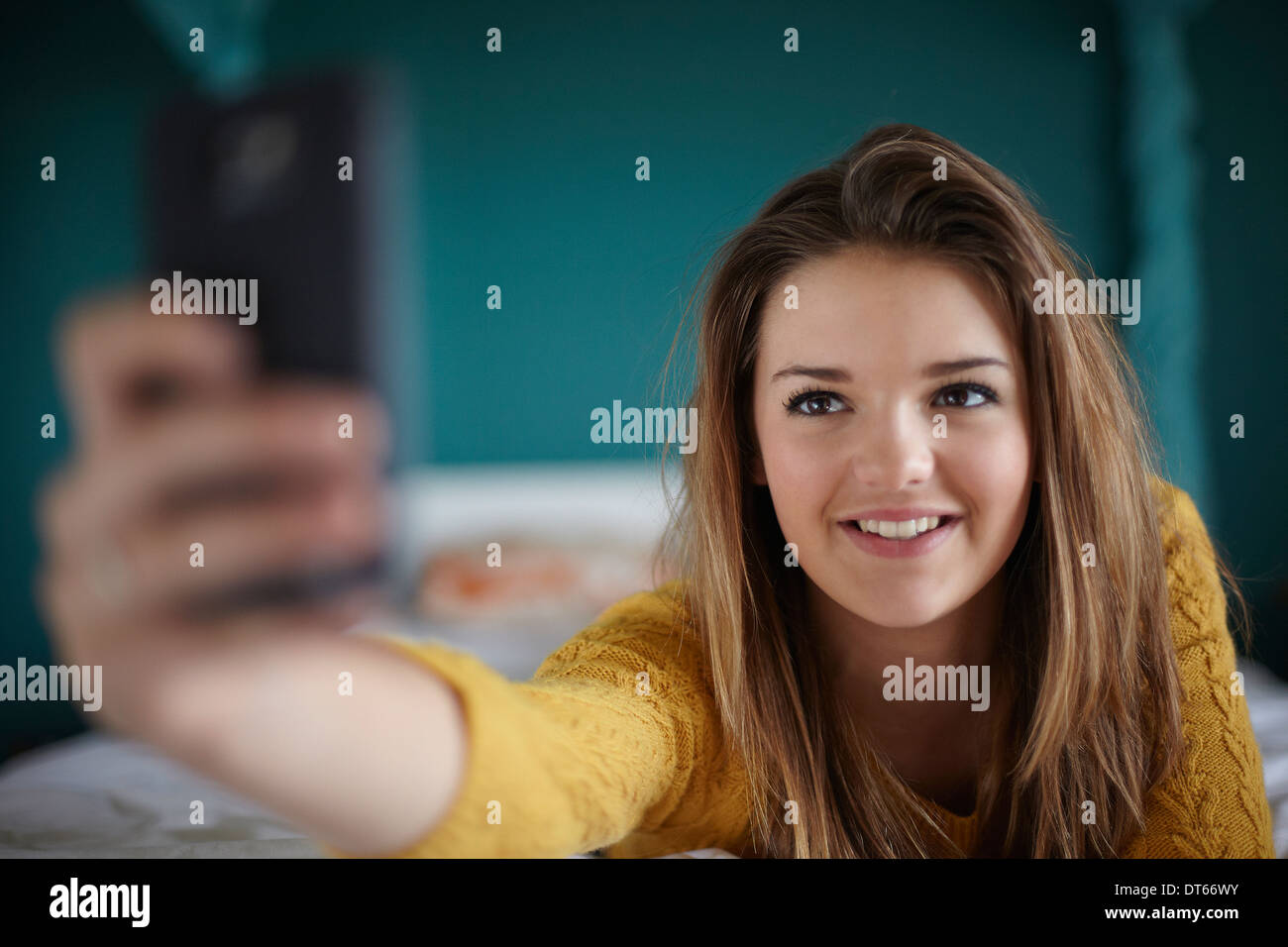 Teenage girl in bedroom taking a selfie Stock Photo