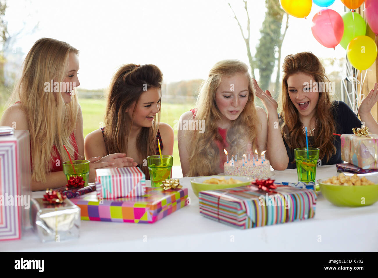 Teenage girl blowing out birthday candles with friends Stock Photo Alamy