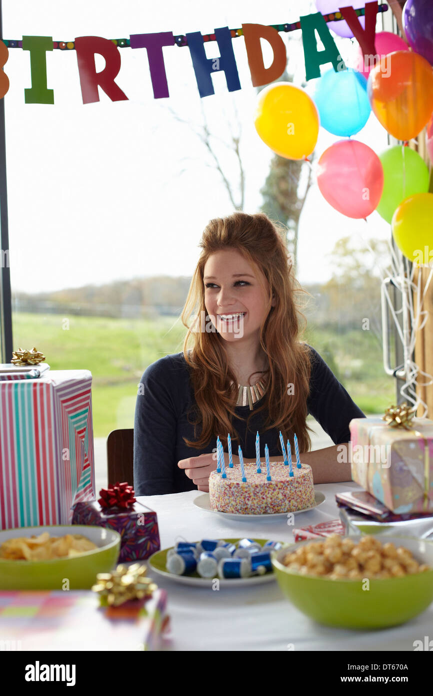 Teenage girl at table with birthday cake Stock Photo