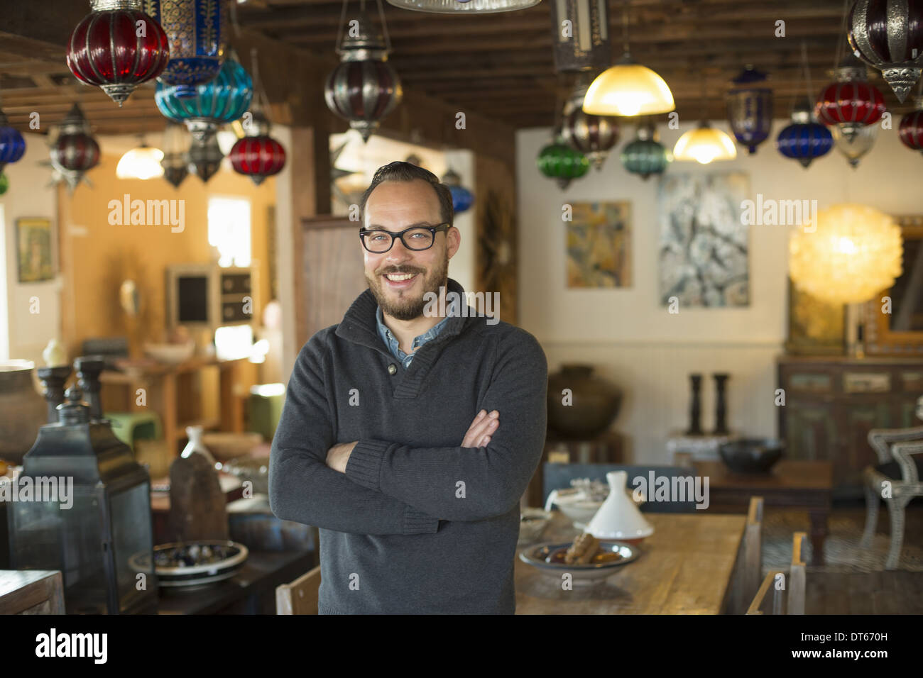 A man standing in a shop full of antique and decorative objects. Antique shop displays. Lighting, glass shades and furniture. Stock Photo