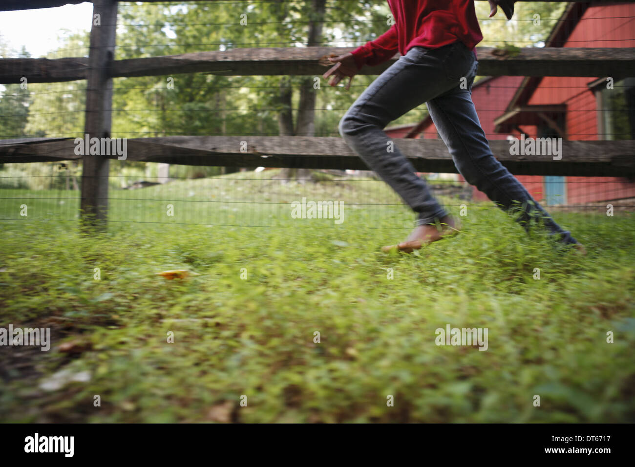 A boy running around a paddock fence outdoors. Stock Photo