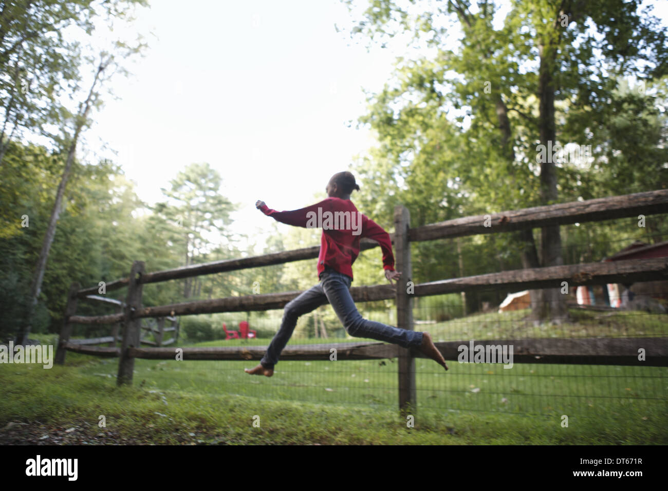 A boy running around a paddock fence outdoors. Stock Photo