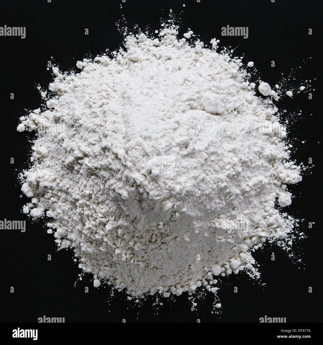Pile of organic unbleached white flour, black backdrop Stock Photo