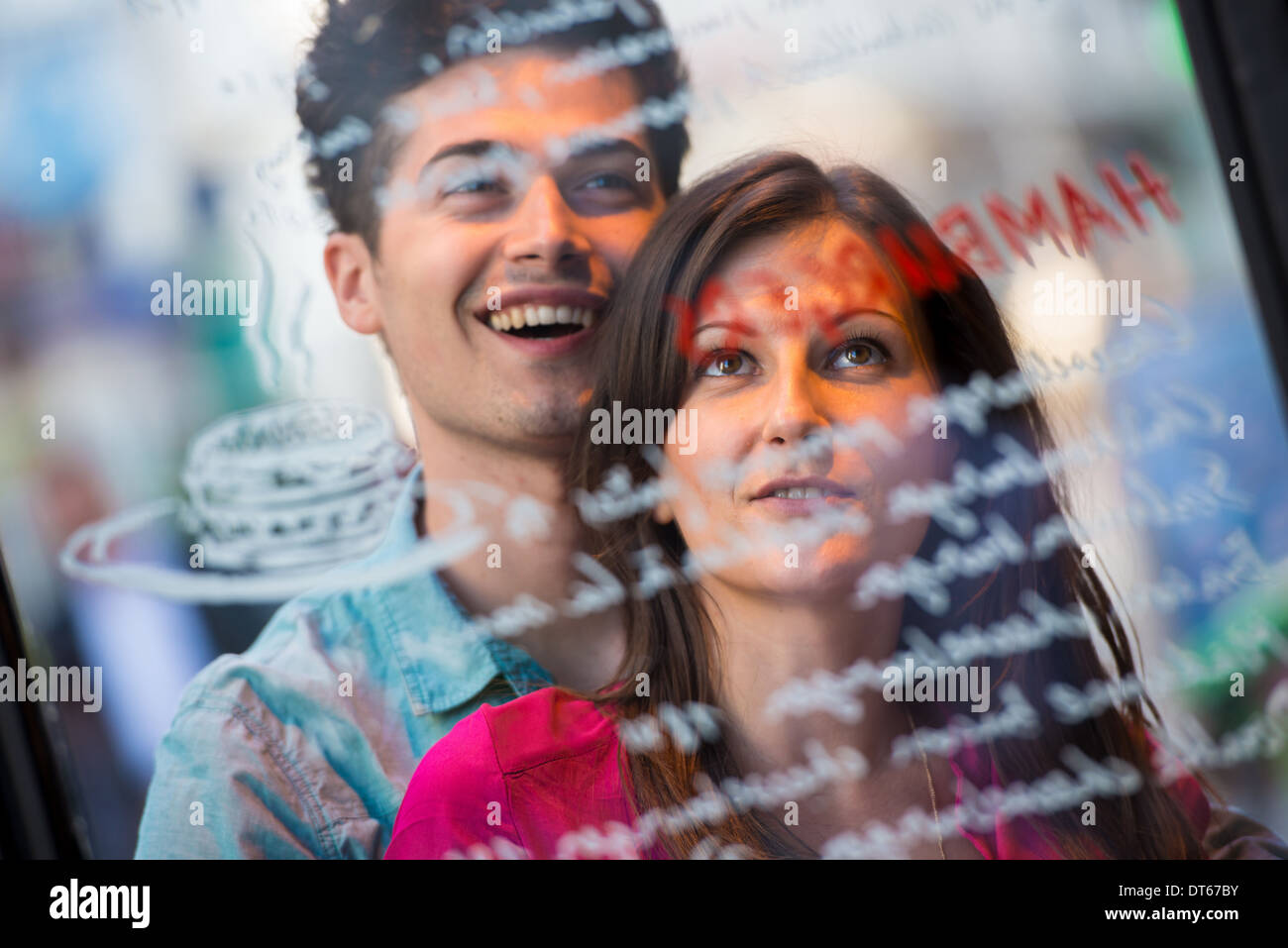 Young couple reading cafe window menu, Paris, France Stock Photo