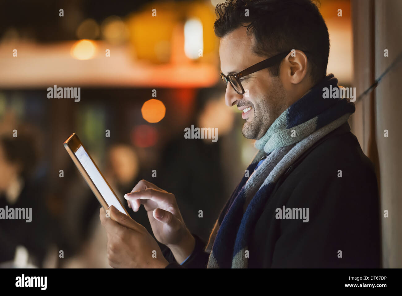 A man in a city at night, looking at a computer tablet. Stock Photo