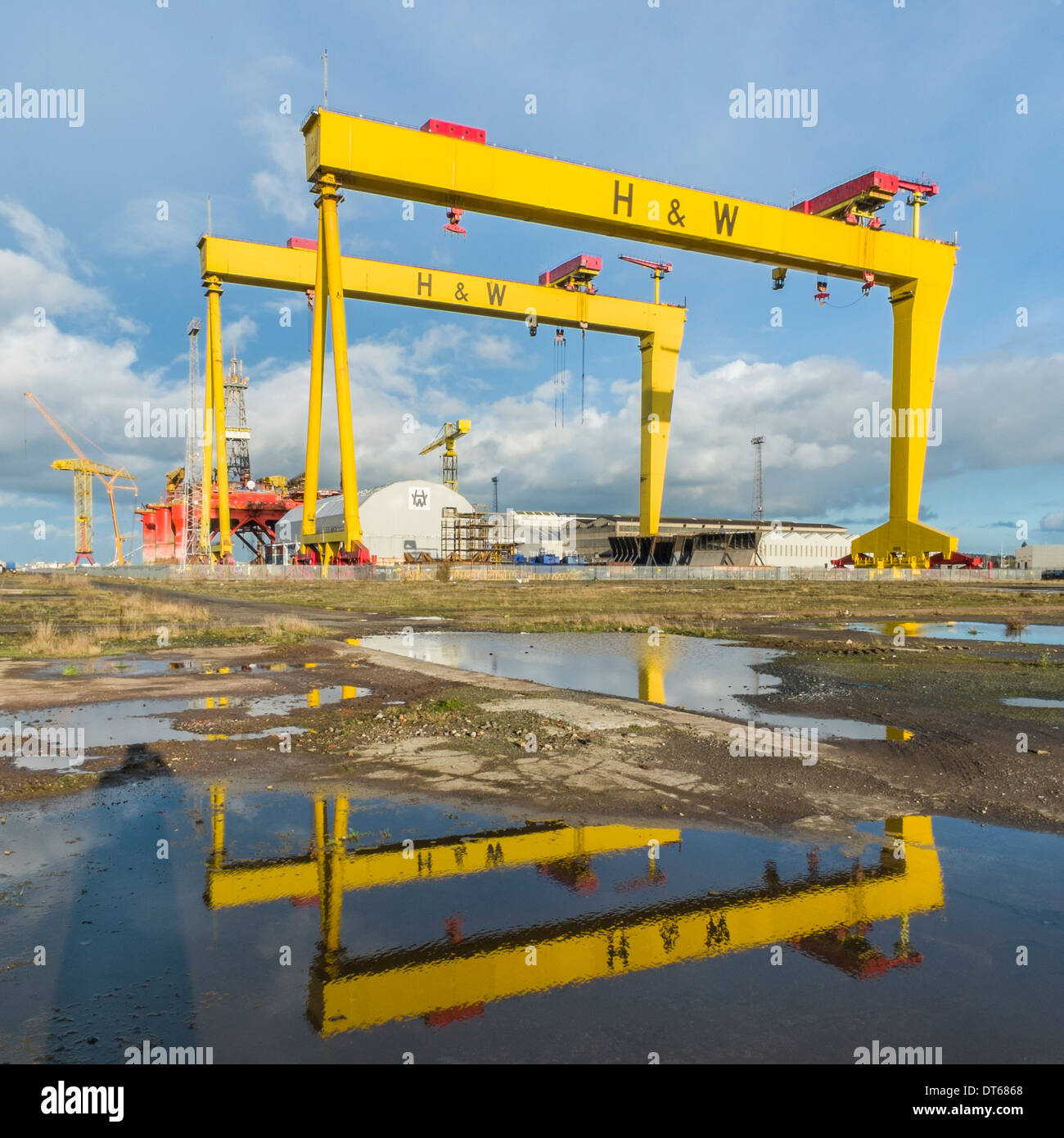View of shipyard cranes, nicknamed Samson and Goliath, in Harland and Wolff Shipyard, Belfast.  Water reflections in foreground. Stock Photo