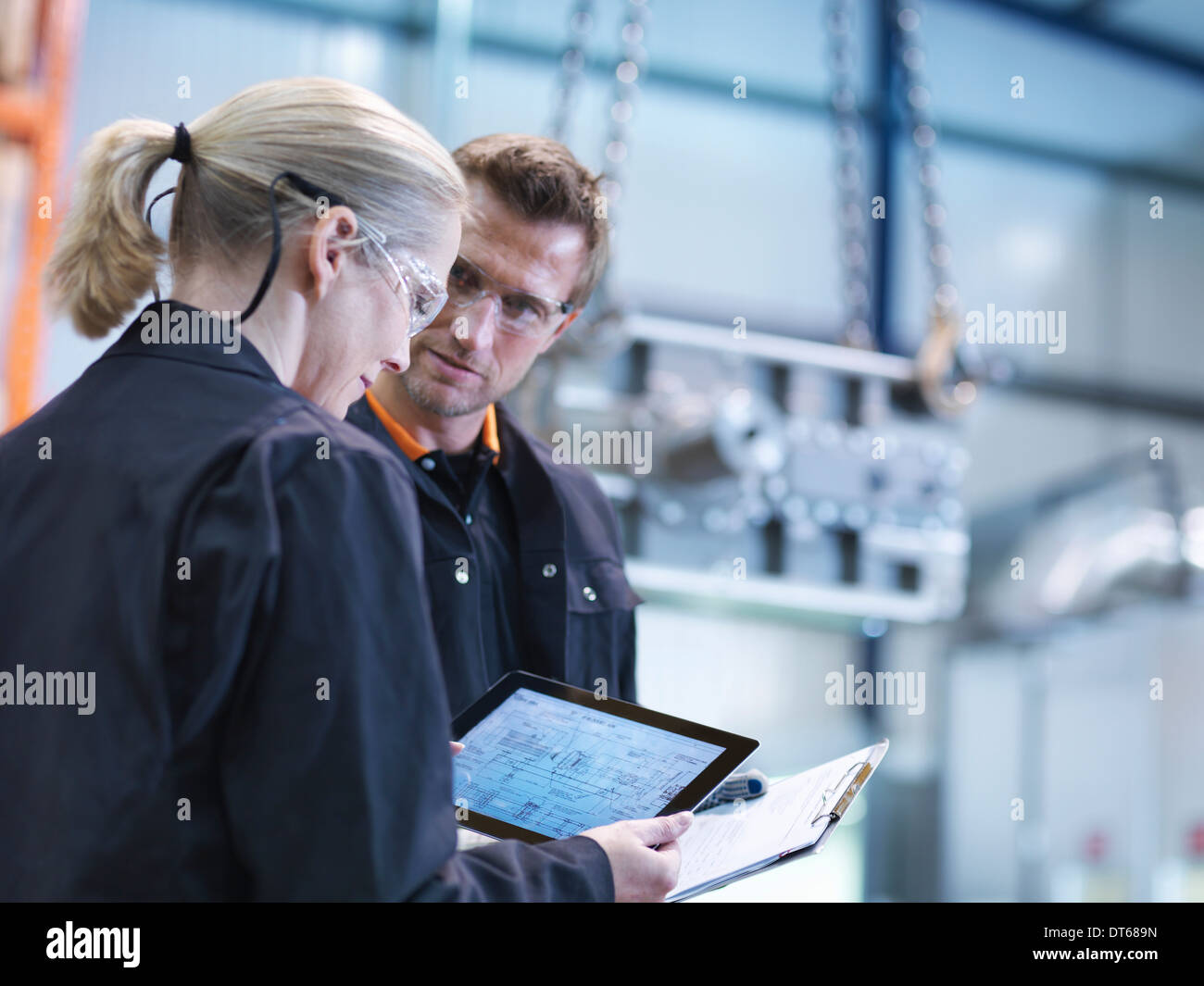 Engineers inspect plans on digital tablet in engineering factory Stock Photo
