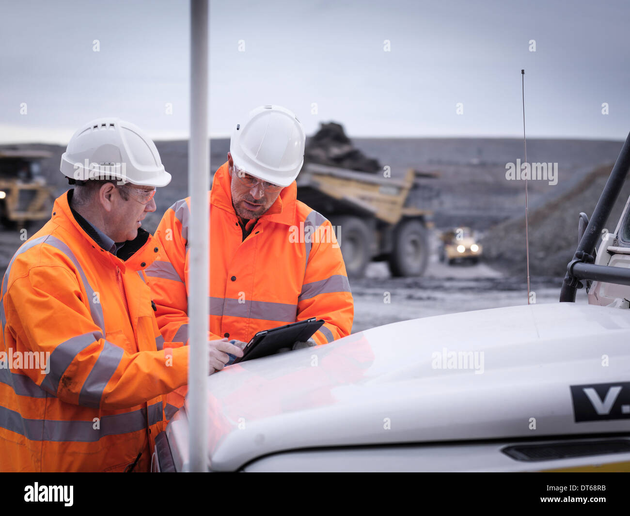 Geologists discuss plans on digital tablet in surface coal mine Stock Photo