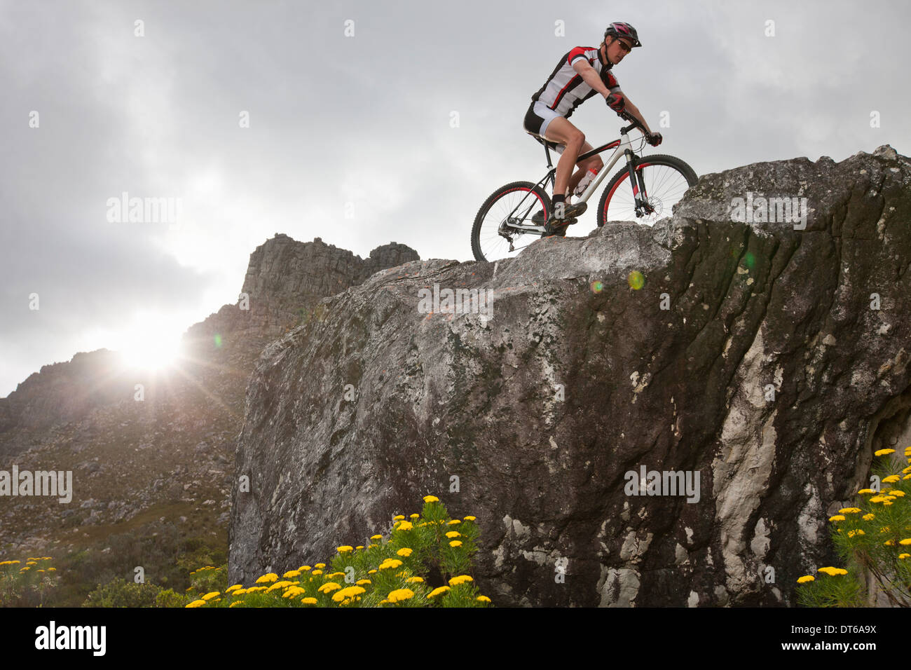 Young man mountain biking on top of rock formation Stock Photo