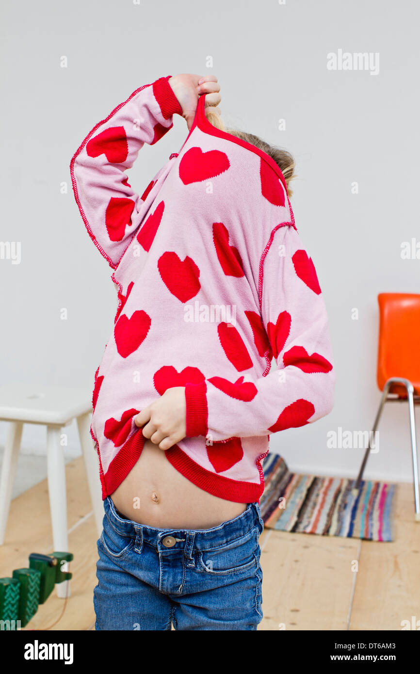 Studio shot of girl hiding in red heart sweater Stock Photo