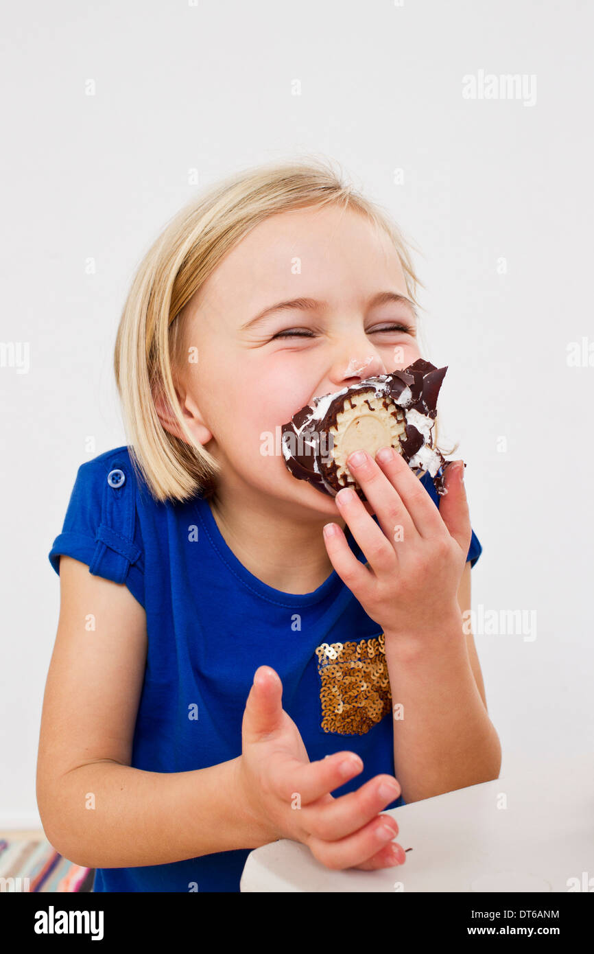 Studio portrait of young girl eating chocolate marshmallow Stock Photo