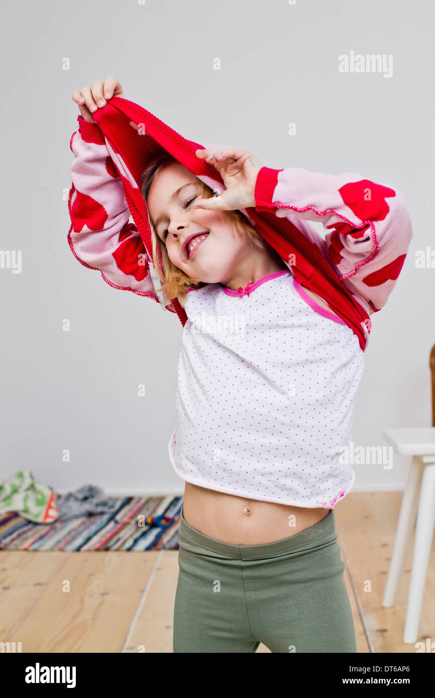 Studio shot of girl pulling off red heart sweater Stock Photo