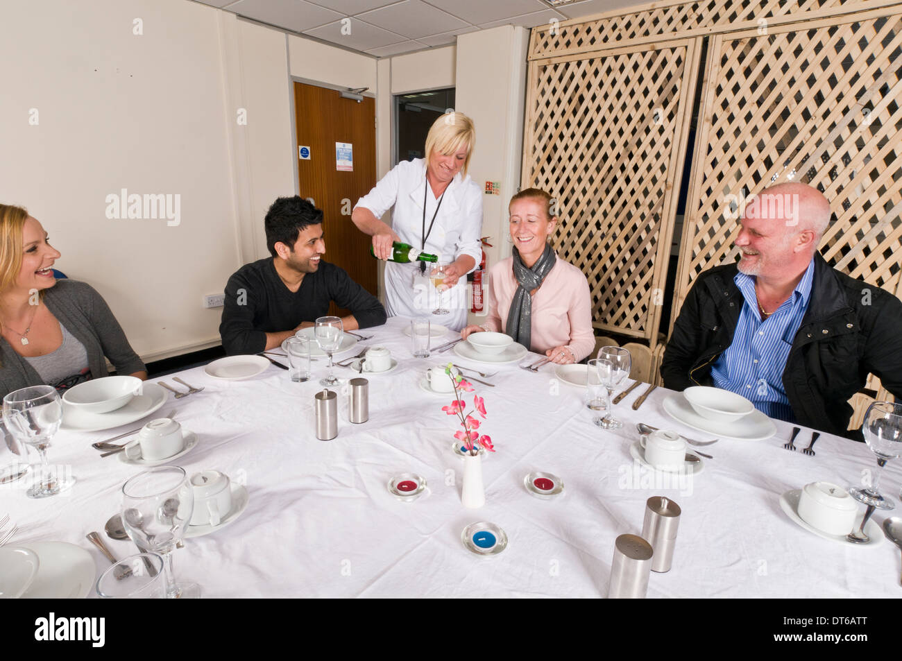 Group of people sat around a dinner table ordering food Stock Photo