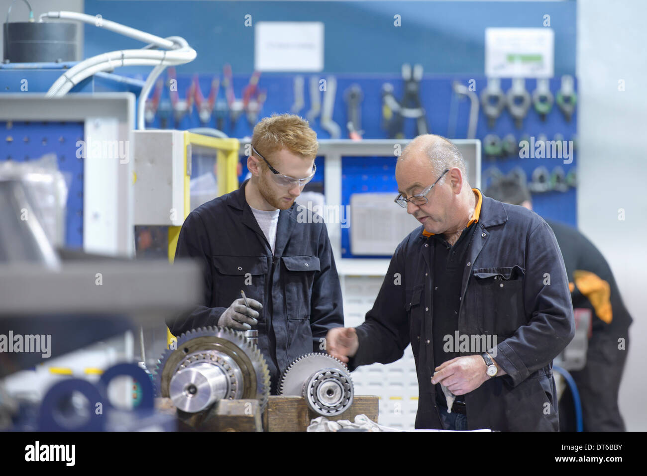 Engineer instructing apprentice at workstation in factory Stock Photo