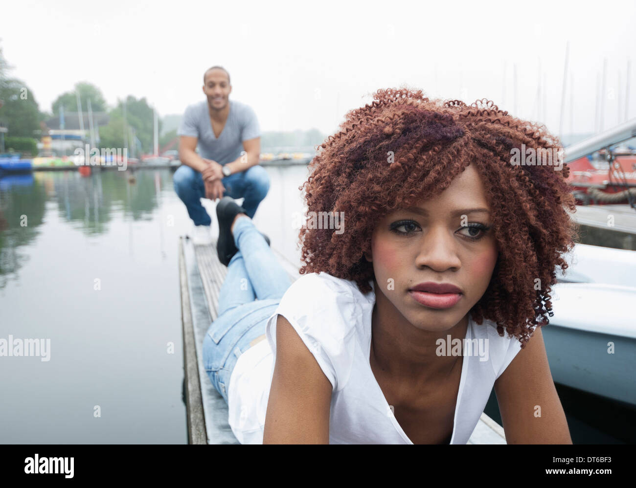 Portrait of sad looking young woman with man in background Stock Photo