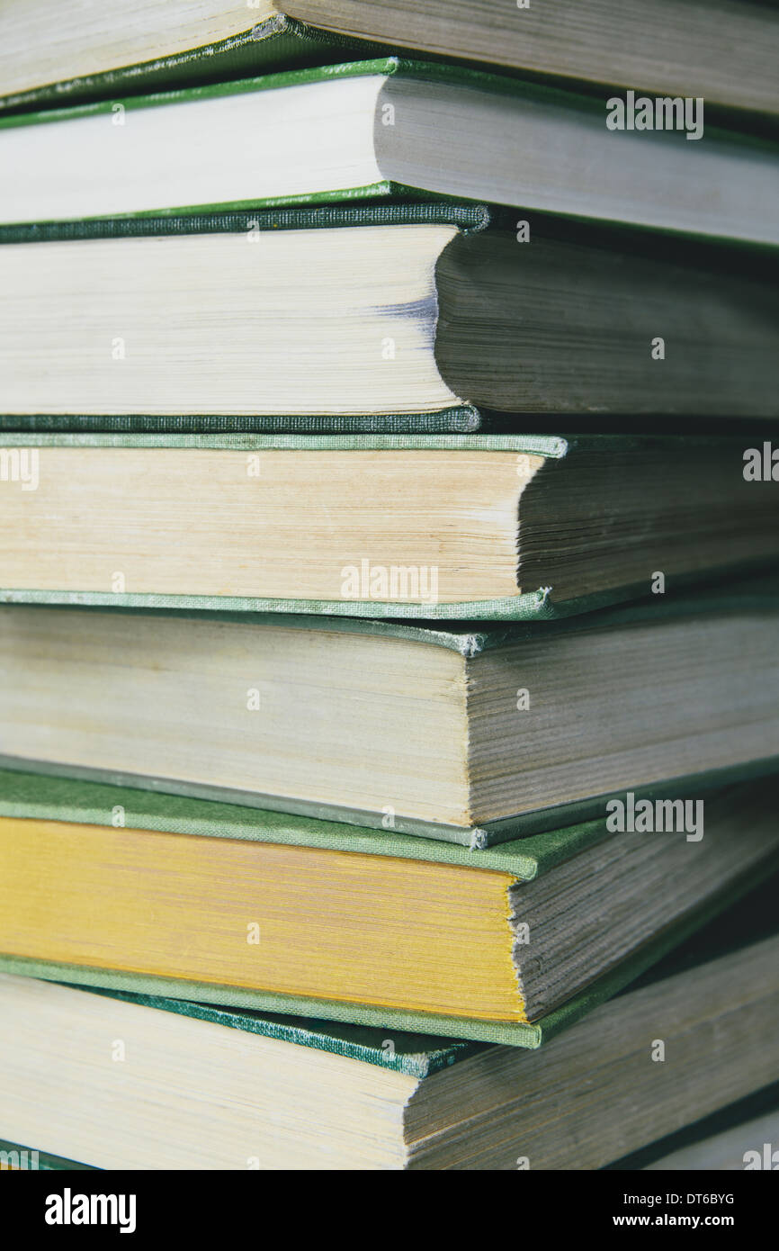 A stack of old hard cover books, with worn edges and paper that is stained or yellowed with age and use. Stock Photo