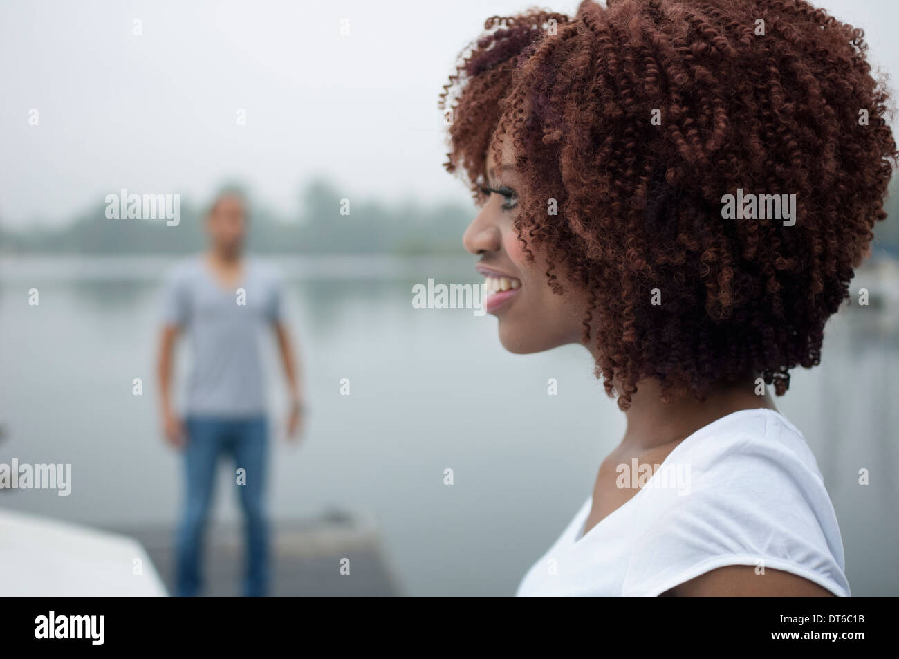 Portrait of young woman smiling with man in background Stock Photo