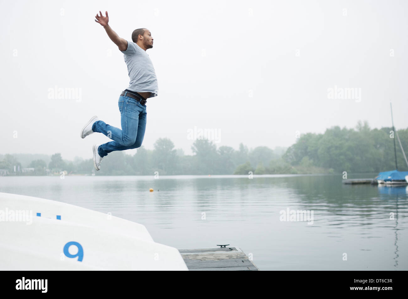 Young man jumping into lake Stock Photo