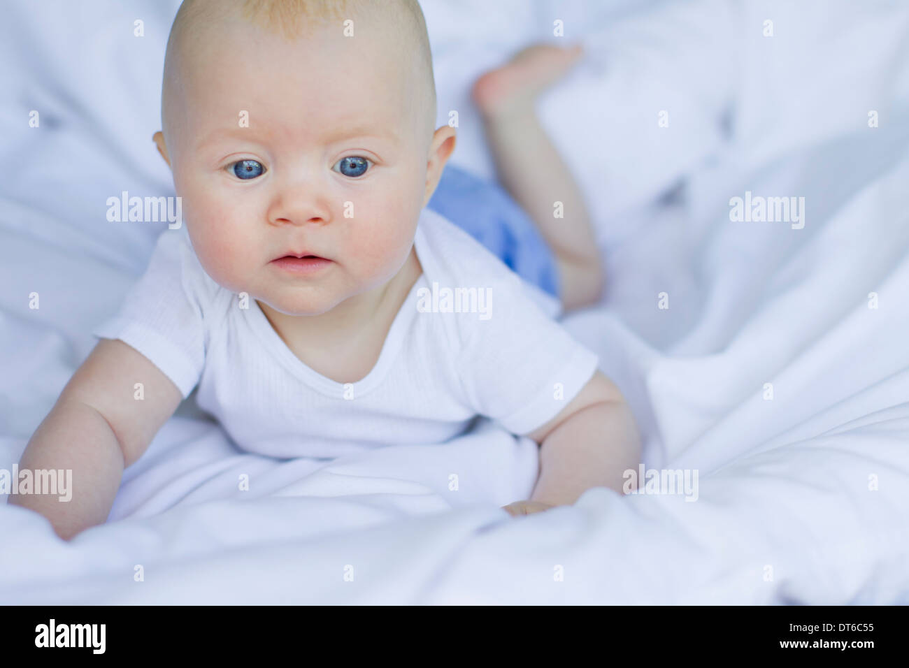 Baby girl lying on bedclothes Stock Photo