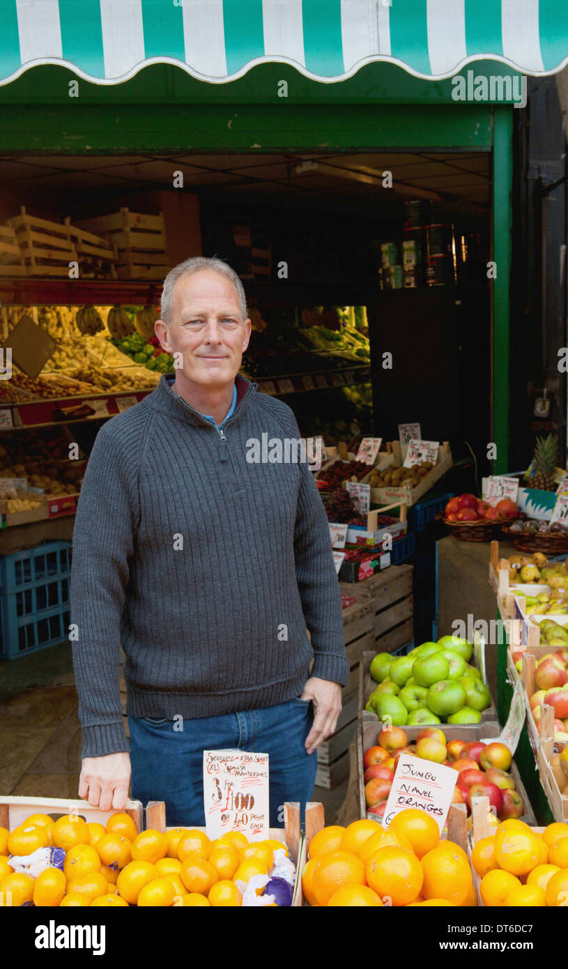 Greengrocer in front of his stall Stock Photo