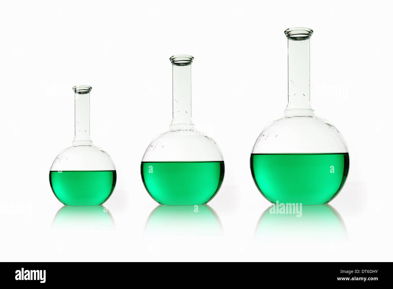 Three rounded shaped scientific chemical flasks holding green liquid, arranged in size order. Stock Photo