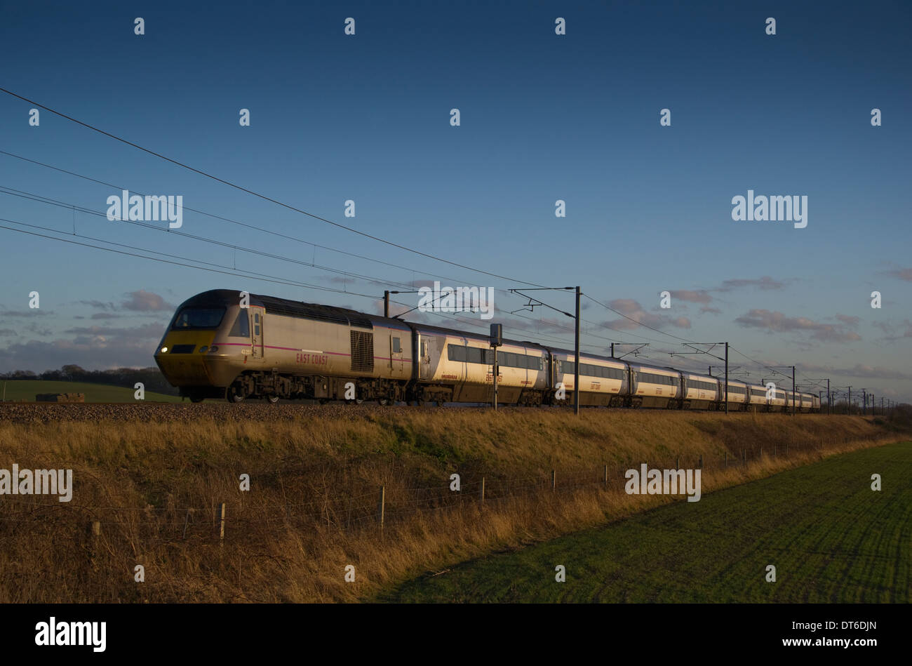 An East Coast Trains service catches the last rays of the evening sun as it sets over the Lincolnshire countryside at Hougham. Stock Photo