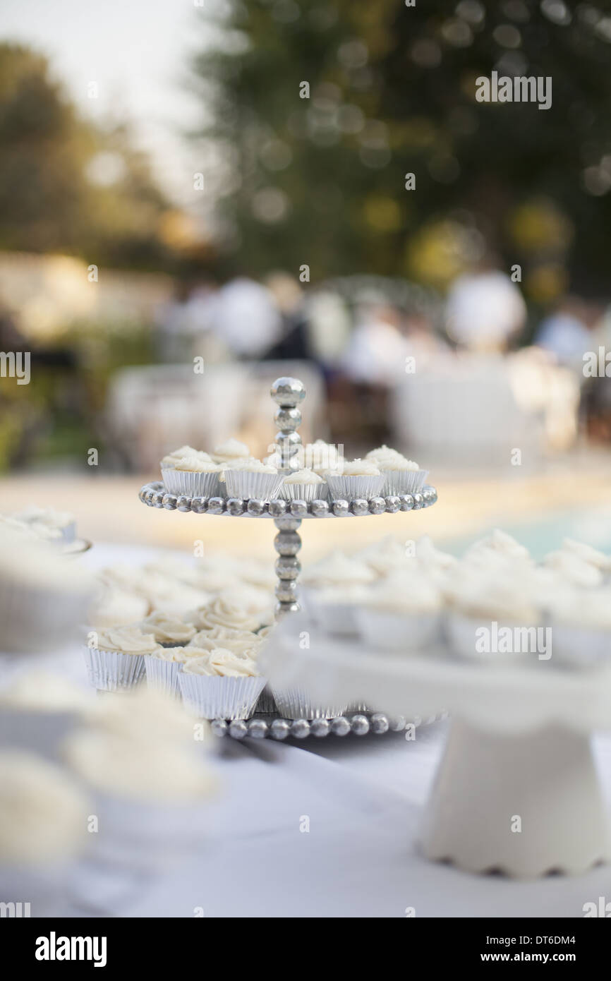 A table laid for a banquet or a wedding breakfast. White table cloth, cake stand, and table setting. Stock Photo