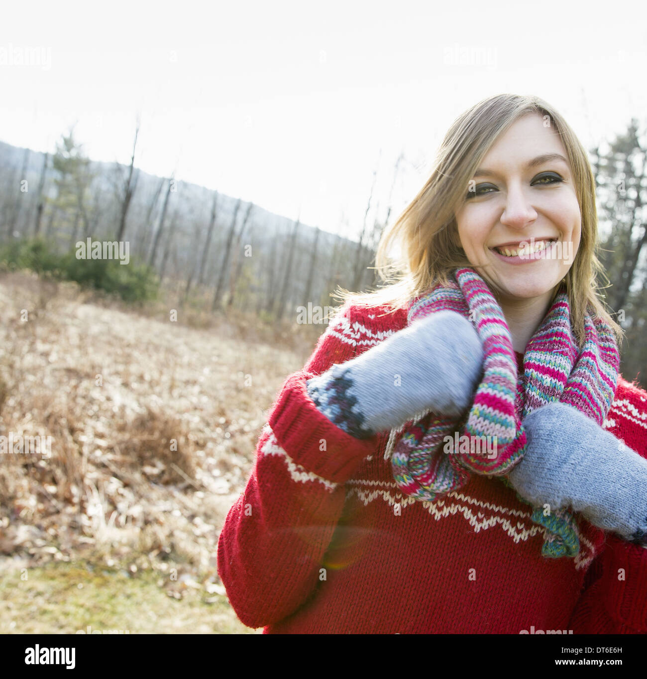 A woman wearing a knitted scarf and woollen mittens outdoors on a winter day. Stock Photo